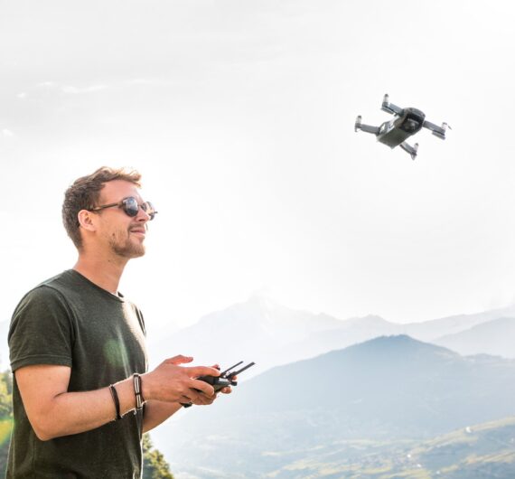 man in dark short sleeved t-shirt and sunglasses flying a drone